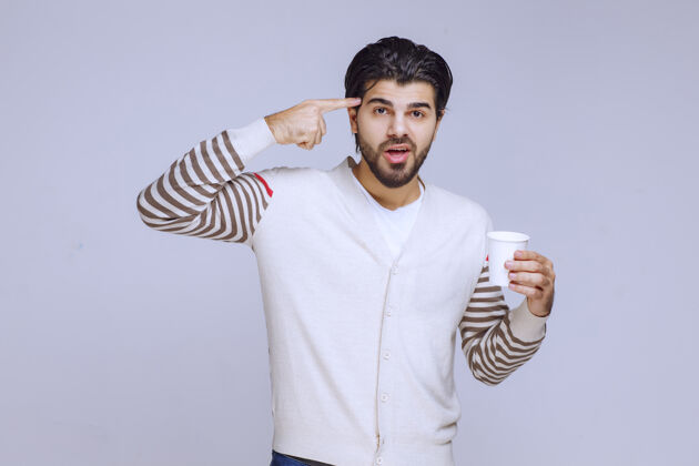 模特一个穿着白衬衫的男人拿着一个咖啡杯思考着员工年轻人类