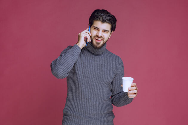 说话一个拿着智能手机和咖啡杯说话的男人电话人体模特员工