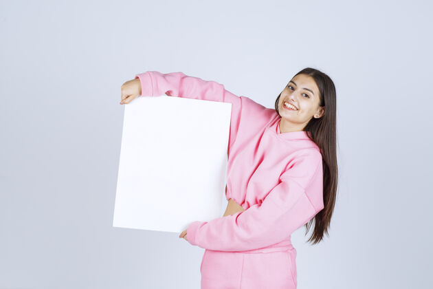 会议穿着粉色睡衣的女孩拿着一个新项目的空白正方形展示板姿势介绍人类