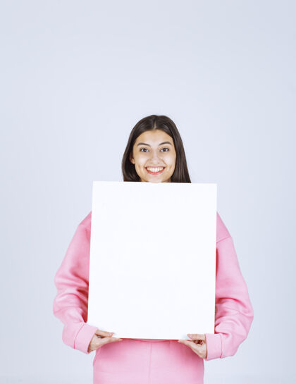 年轻穿着粉色睡衣的女孩 手里拿着一块空白的方形展示板项目聪明人类