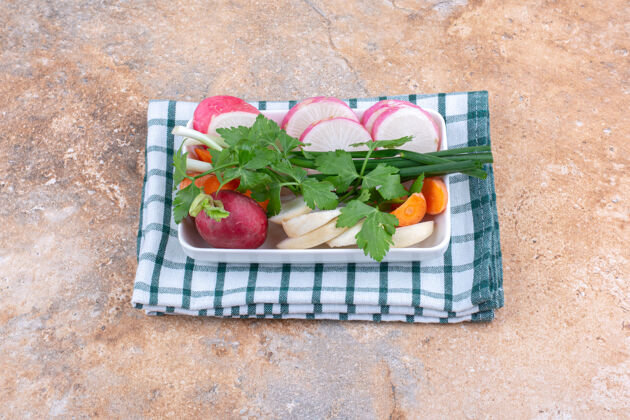 蔬菜新鲜沙拉原料包在一个折叠毛巾在大理石表面上的盘子毛巾什锦胡萝卜