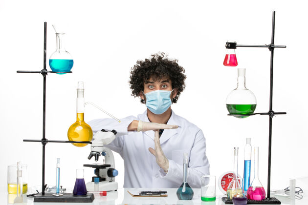 解决方案正面图：男药剂师穿着医疗服 戴着面罩 坐在不同的溶液中 在空白处摆姿势化学不同的科学