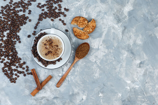 杯子一套饼干 咖啡豆 磨碎的咖啡 肉桂棒和咖啡在一个灰色石膏背景杯顶视图早餐食物马克杯