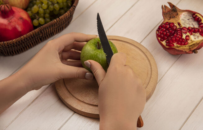 苹果侧视图：女人在砧板上切青苹果 在白墙上切石榴板水果石榴