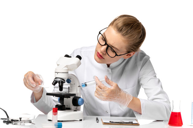 病毒前视图穿着白色医疗服的女医生戴着手套拿着针剂 在空白处使用显微镜使用工作注射