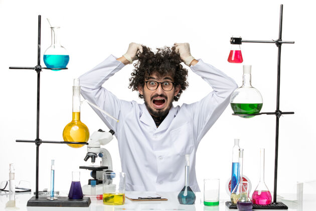 只是前视图穿着医疗服的男性化学家正坐在桌子前面 在空白处放着溶液餐桌实验室医生