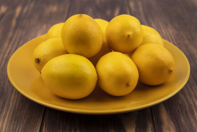 食物新鲜的黄色皮肤柠檬在木制表面上的黄色盘子顶视图新鲜营养柑橘