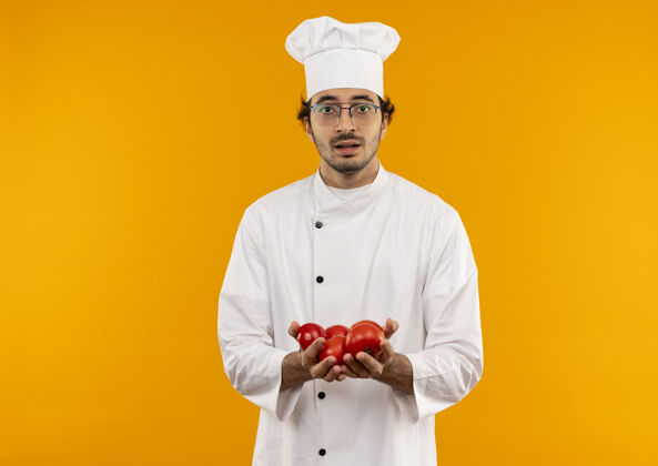 制服年轻的男厨师穿着厨师制服 戴着拿着西红柿的眼镜男性烹饪男