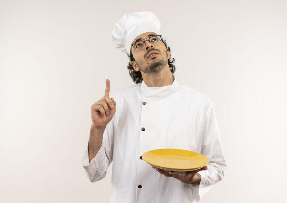 厨师看着上来的年轻男厨师穿着厨师制服和眼镜拿着盘子指着上来向上眼镜盘子