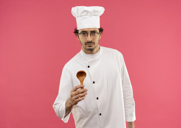 制服悲伤的年轻男厨师穿着厨师制服 戴着眼镜拿着勺子戴着男男