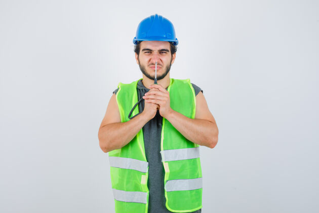 工人穿制服的年轻建筑工人用螺丝刀按鼻子 看上去很滑稽 正视图鼻子修理工西班牙裔