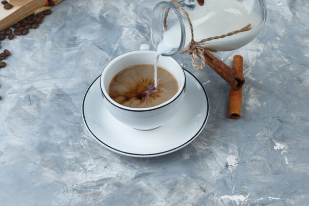 牛奶高角度观看倒入牛奶的咖啡杯 咖啡豆 肉桂棒的灰色背景水平自然摩卡角度