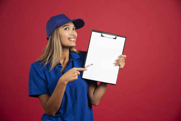 女人穿着蓝色制服的年轻女子用铅笔指着剪贴板人类制服帽子