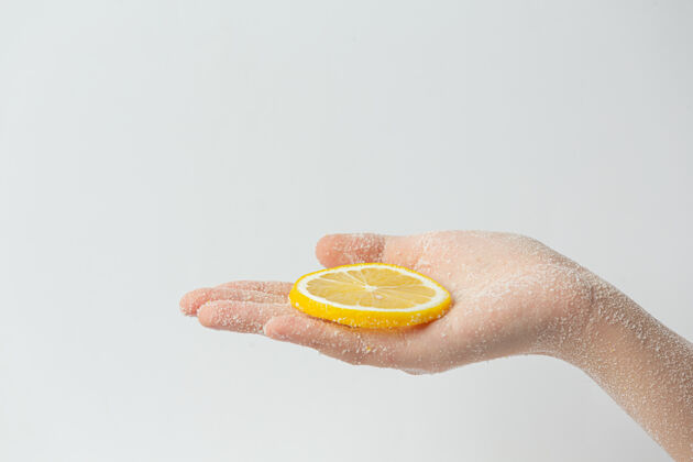 护理年轻女子用天然柠檬磨砂膏擦手上的白色表面皮肤剥皮柠檬