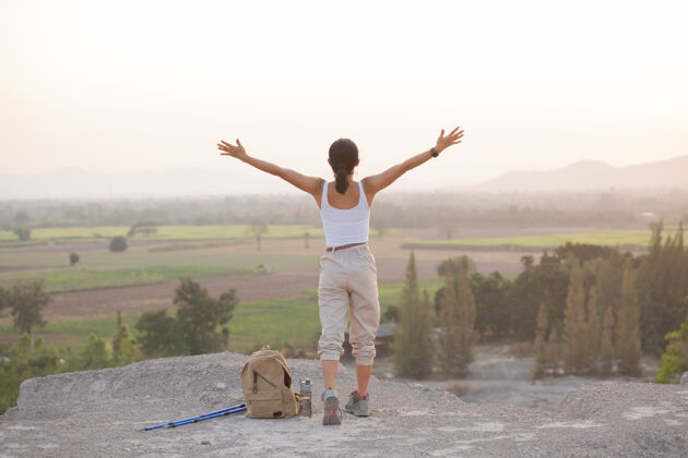 徒步旅行者徒步旅行时 一位妇女在山顶举手 站在岩石山脊上的电线杆眺望山谷人运动亚洲人