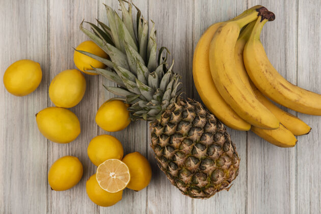美味顶视图新鲜水果 如菠萝香蕉和柠檬隔离在一个灰色的木制表面木材美味配料