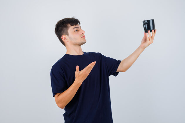 互联网一幅年轻人身着黑色t恤展示一杯茶 面带沉思的肖像年轻人休闲笔记本电脑