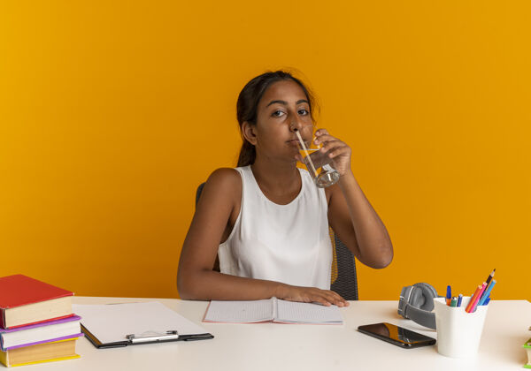 年轻人坐在书桌旁拿着学习用具喝水的年轻女学生女人工具喝酒
