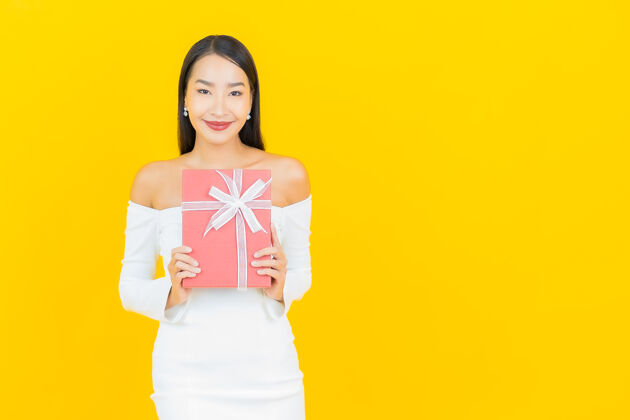 盒子黄墙上挂着红色礼盒的亚洲商界年轻美女画像脸年轻有趣