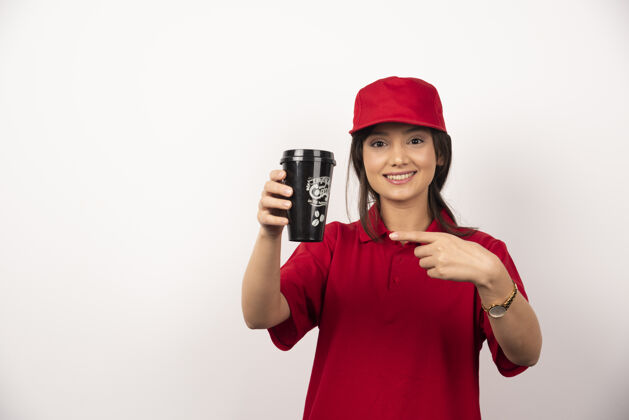 工人穿着红色制服的女人在白色背景上展示一杯咖啡制服表演工作