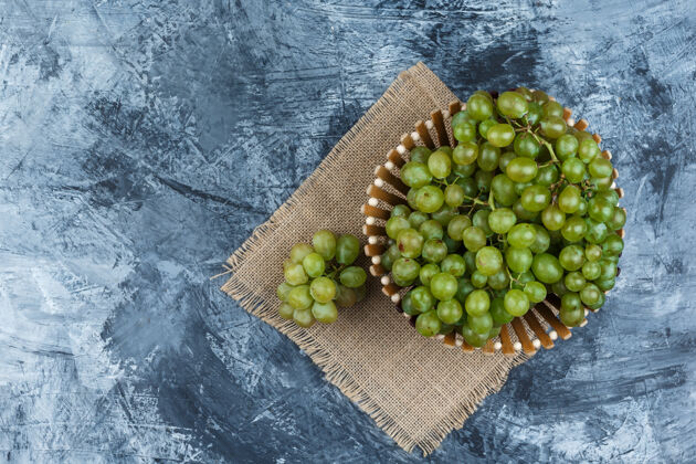 垃圾把绿色的葡萄平放在篮子里 放在垃圾桶和一块布袋的背景上水平秋天健康浆果