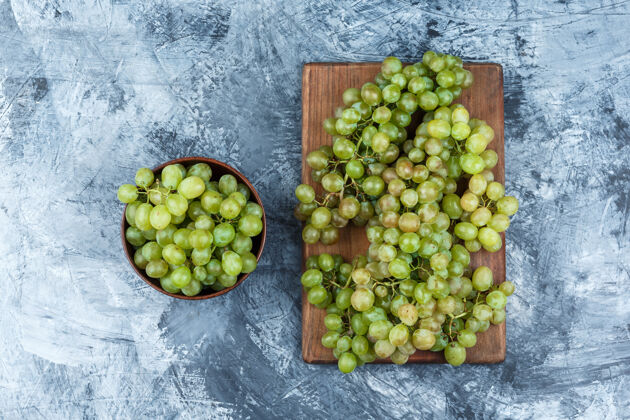 素食绿色的葡萄在一个碗平放在肮脏的石膏和砧板背景板新鲜有机