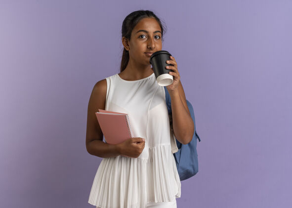 拿着年轻的女学生背着背包拿着笔记本和咖啡紫色女学生背包