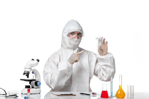 套装正面图穿着防护服的男医生拿着空烧瓶在浅白的空间里病毒药品实验室外套