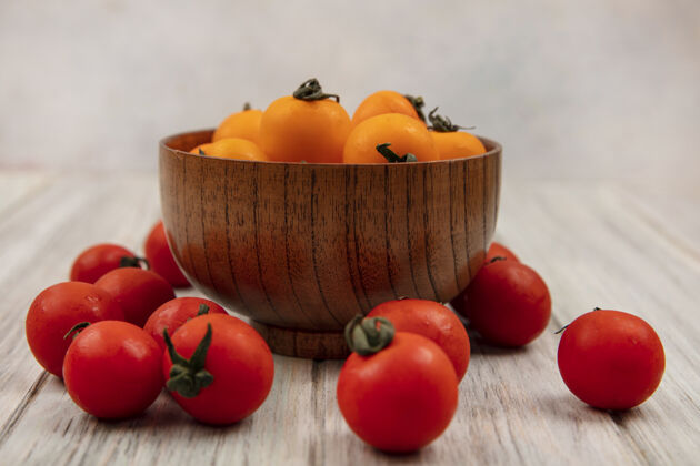 新鲜侧视图软橙色西红柿在一个木碗与红色西红柿隔离在一个灰色的木制表面农业软健康
