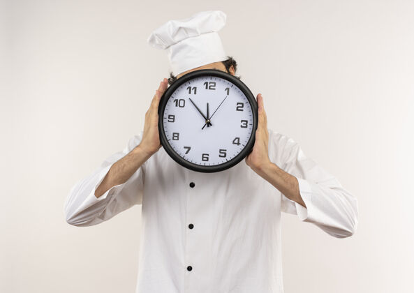 眼镜年轻的男厨师穿着厨师制服 戴着眼镜 脸上戴着隔离在白色墙上的挂钟年轻盖脸