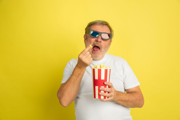 专业一个白人男人在看电影 穿着黄色的爆米花和3d眼镜时尚工作财务