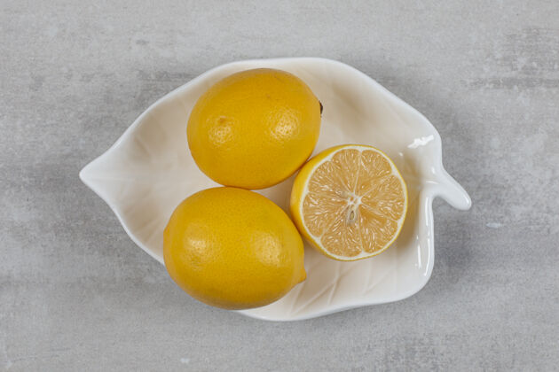 盘子在大理石表面的盘子里放两个半柠檬风味蔬菜新鲜