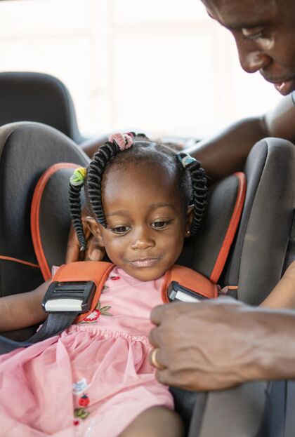 小父亲把女儿放在儿童车的椅子上小非洲黑人女孩