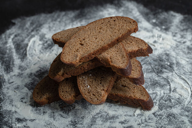 面团新鲜出炉的棕色面包片 以白色面粉为背景面粉健康制作
