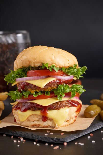 三明治自制汉堡包或汉堡配新鲜蔬菜 奶酪生菜和蛋黄酱 炸薯条放在黑石桌上的牛皮纸上快餐和垃圾食品的概念土豆牛肉烤架
