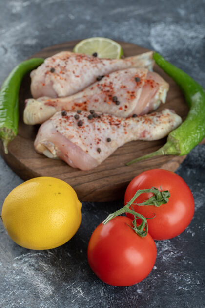 生肉新鲜有机番茄和柠檬配生鸡腿的垂直照片烹饪准备蔬菜