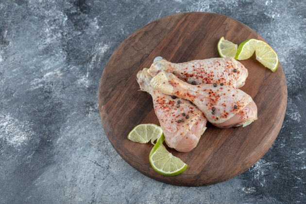 晚餐在灰色背景上的木板上腌制生鸡腿的特写照片海洋烹饪烧烤