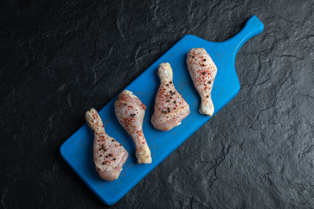 鸡腿蓝色木板上生鸡腿的俯视图洋葱烧烤晚餐