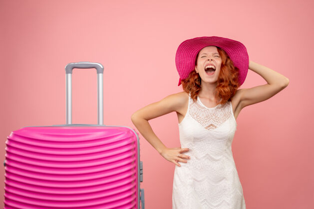 时尚年轻的女性游客与粉红色的帽子和粉红色的墙壁上的包的正面视图夏天包可爱
