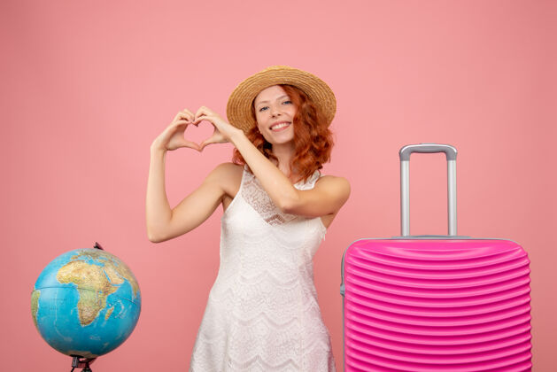 漂亮年轻女性游客的正面图 浅粉色的墙上挂着粉色的包前面头发时尚