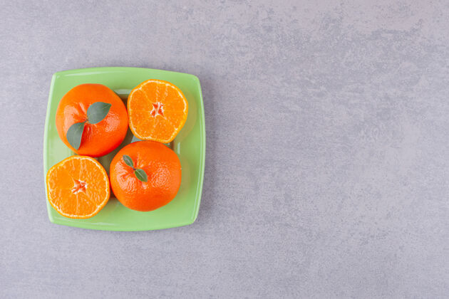 水果整个橘子和切成片的橘子放在绿色的盘子里热带健康多汁