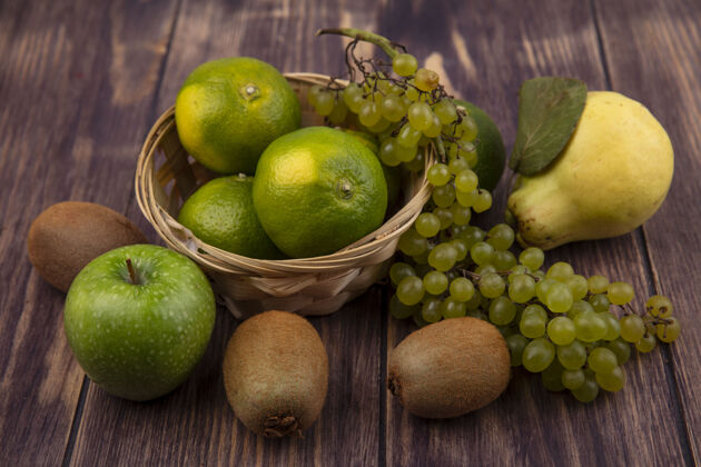 梨前视图梨与猕猴桃 橘子 苹果和葡萄在一个篮子在一个木墙上篮子水果甜点