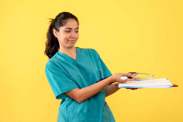 人穿制服的女医生在黄墙上给纸的正面图女医生人纸