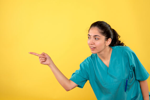人年轻女医生用手指指着黄色墙壁的正视图人快乐成人