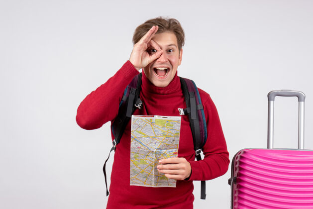 微笑男游客的正面图 白色墙上有背包和地图夏天快乐背包