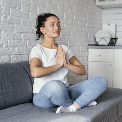放松坐在沙发上冥想的全镜头女人瑜伽内心生活方式