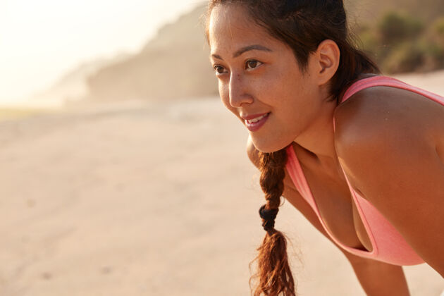 放松一个留着长发 梳着辫子 穿着休闲背心的亚洲美女的不规则剪裁的照片锻炼训练沙滩