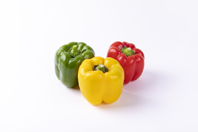 饮食黄色 红色和绿色的保加利亚胡椒被隔离在一张白色的桌子上闪亮配料沙拉