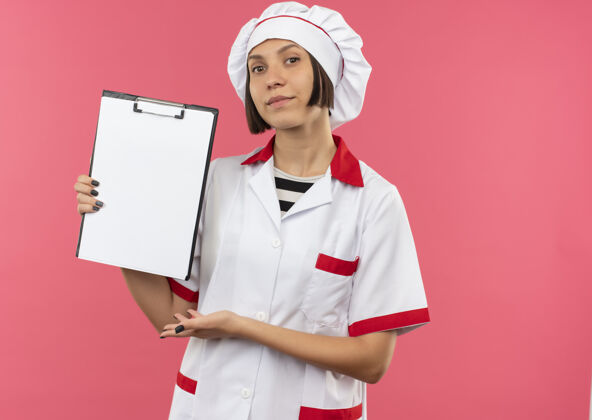 复制自信的年轻女厨师身着厨师制服 用手指着粉色的剪贴板 并留有复印空间剪贴板女粉红