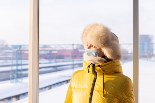 感染年轻女子在火车站戴着防护面具 脸上穿着冬装的乘客城市Quarantine预防